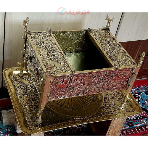 نمای نزدیک قلم‌زنی ظریف و نقش گل و مرغ روی منقل برنجی سیاه‌شده هنر ظریف.